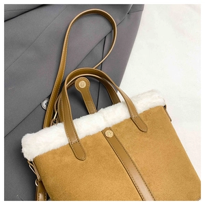 Close-up of brown suede handbag with white faux fur trim and gold metal hardware detail