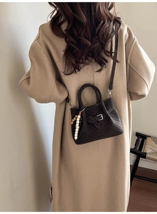 Chic dark brown suede handbag with V-quilted texture and bead charm on camel coat