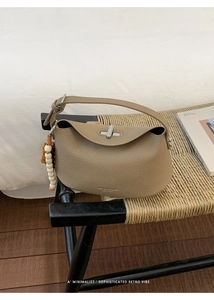 Close-up of taupe litchi leather bag with metal buckle and stylish beaded charm