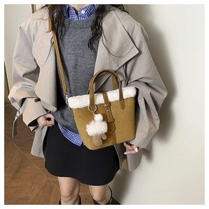 Detail view of a brown suede handbag with faux fur trim and heart-shaped plush charm