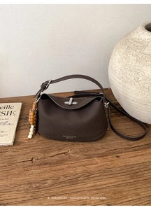 Detailed macro view of dark brown pebble leather bag with silver twist lock and retro charm