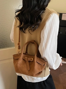 Sac bandoulière en daim matelassé marron avec chaîne et boucle porté par un mannequin