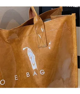 Detail of caramel tote bag with transparent glossy overlay and white TOTE BAG text