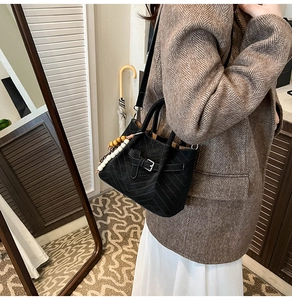 Detail of black suede bag with V-shaped stitching and colorful bead accessory