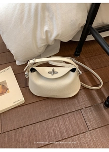 Detail view of cream white lychee grain leather bag with a silver metallic twist lock