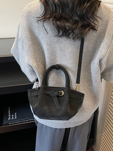 Sac seau matelassé noir élégant avec chaîne dorée porté par un mannequin à l'épaule
