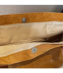 Close-up of orange textured tote bag with magnetic snap closure and interior zip pocket