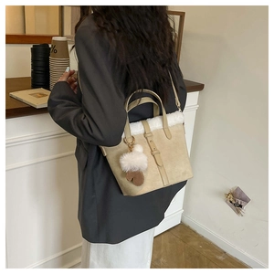 Detail of beige suede handbag with faux fur trim and cute glove pendant accessory