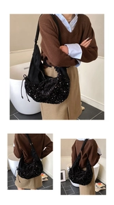 Detail of black sequined crossbody bag with glossy texture and drawstring side detail