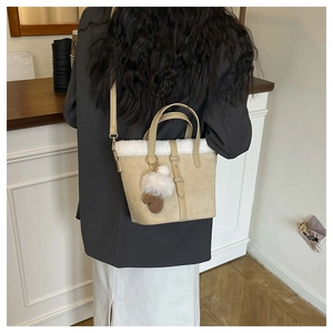 Detail of beige bucket bag with white plush trim and cute glove pendant accessory