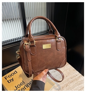 Detail of vintage brown handheld bowling bag with golden hardware and adjustable strap