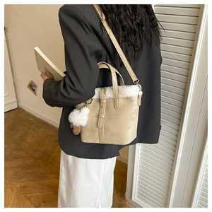 Beige bucket bag featuring white faux fur trim and fluffy pom-pom charm detail