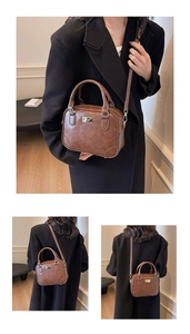 Detail of vintage brown leather satchel with gold hardware and adjustable strap