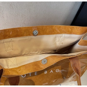 Detail of caramel tote bag showing magnetic snap closure and woven handle straps