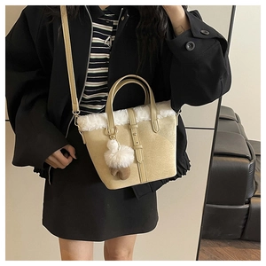 Detail view of a suede bucket bag with white faux fur trim and a cute plush bear paw charm