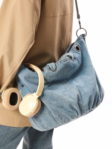 Blue denim crossbody tote bag with adjustable strap and cream headphones for urban style