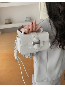 Detailed view of a white leather square crossbody bag with a silver metal clasp buckle