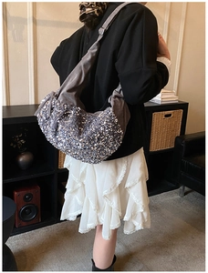 Detailed back view of a grey pleated sequin hobo bag worn by a model in a cozy room
