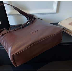 Détail du logo gaufré et de la texture cuir mat sur un grand sac cabas marron foncé
