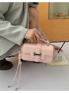 Detail of light pink leather crossbody bag with silver buckle and long tassel charm