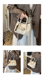 Detail of cream woven tote bag with V-quilt pattern, wooden bead charm and long strap