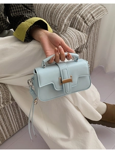 Close-up of light blue leather handbag with woven strap detail and silver metal lock