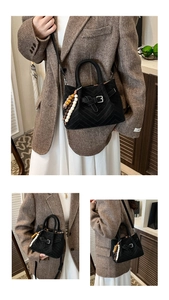 Detail of black chevron bucket bag with wooden bead pendant and removable strap