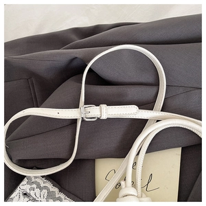 Detail of white litchi pattern leather strap with silver buckle and knot decoration