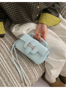 Detail of light blue square handbag with silver T-lock and detachable shoulder strap
