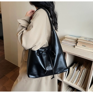 Détail d'un grand sac cabas noir vintage avec un nœud décoratif et une étiquette de logo