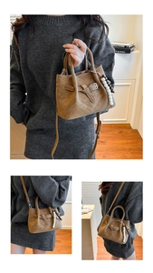 Detail of brown vintage crossbody bag with V-stitching, beads charm and shoulder strap