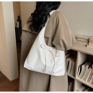 Sac hobo beige minimaliste avec détail de nœud porté par un mannequin en intérieur