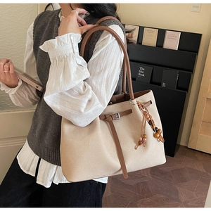 Detail of canvas tote bag with brown leather straps and colorful wooden bead tassel