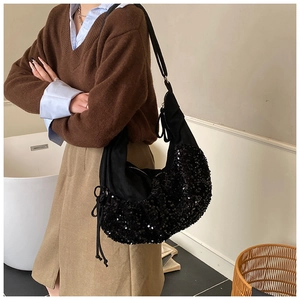 Detail of a black sequined crescent shoulder bag featuring a drawstring side and zipper