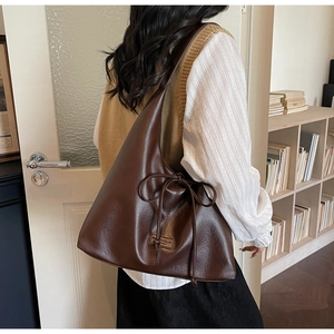 Close-up of a dark brown PU leather tote bag with decorative bow and brand label detail