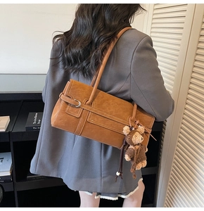 Detailed view of vintage brown shoulder bag with silver buckle and cute teddy bear charm