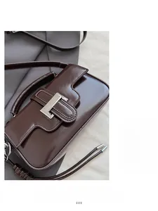 Close-up of shiny dark brown leather crossbody bag with vintage silver metal buckle