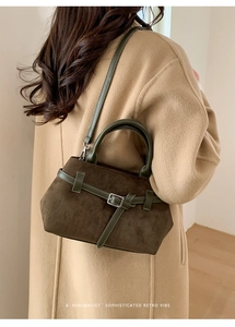 Détail du sac cabas en daim vert olive avec lanières en cuir sur un manteau en laine