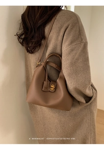 Detail of dark brown lychee textured leather bag with gold twist lock on wool coat