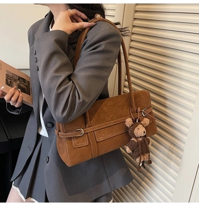 Detail of vintage brown suede tote bag with cute teddy bear charm and leather accents