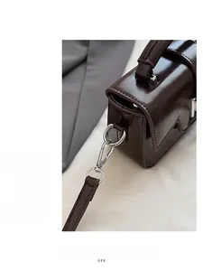 Detailed close-up of dark brown glossy patent leather bag with silver metal hardware