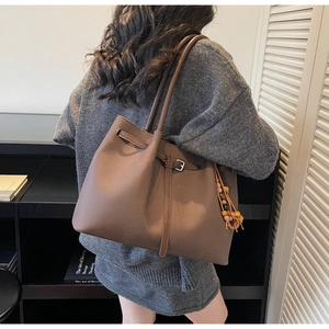Detail of dark brown tote bag featuring ethnic beaded tassels and crossbody strap detail