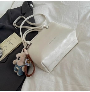 Creamy white bucket bag with pebble leather texture and a cute plush bear pendant accessory