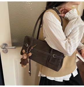 Detail of vintage brown leather tote bag with white stitching and cute bear charm pendant