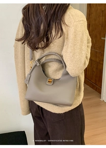 Detailed macro of grey lychee-textured leather bag with metallic twist-lock and shoulder strap