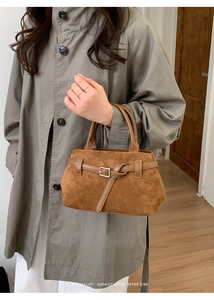 Nahaufnahme der braunen Wildleder-Tote-Bag im Vintage-Stil mit Silberschnalle am grauen Mantel