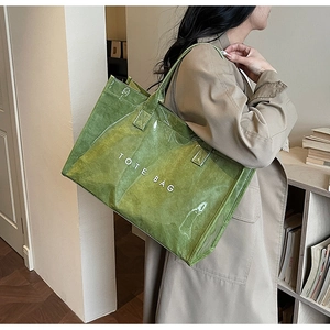 Close-up of green Tyvek tote bag with PVC layer and white TOTE BAG text shown on model