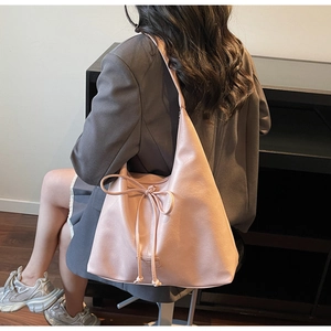 Modèle avec sac cabas en cuir rose avec cordon de serrage et large bandoulière élégante