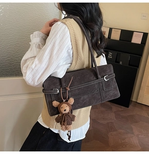 Detail of vintage brown shoulder bag with contrast stitching and teddy bear charm