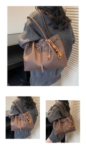 Close-up of brown leather tote bag with decorative side straps and vintage wooden beads
